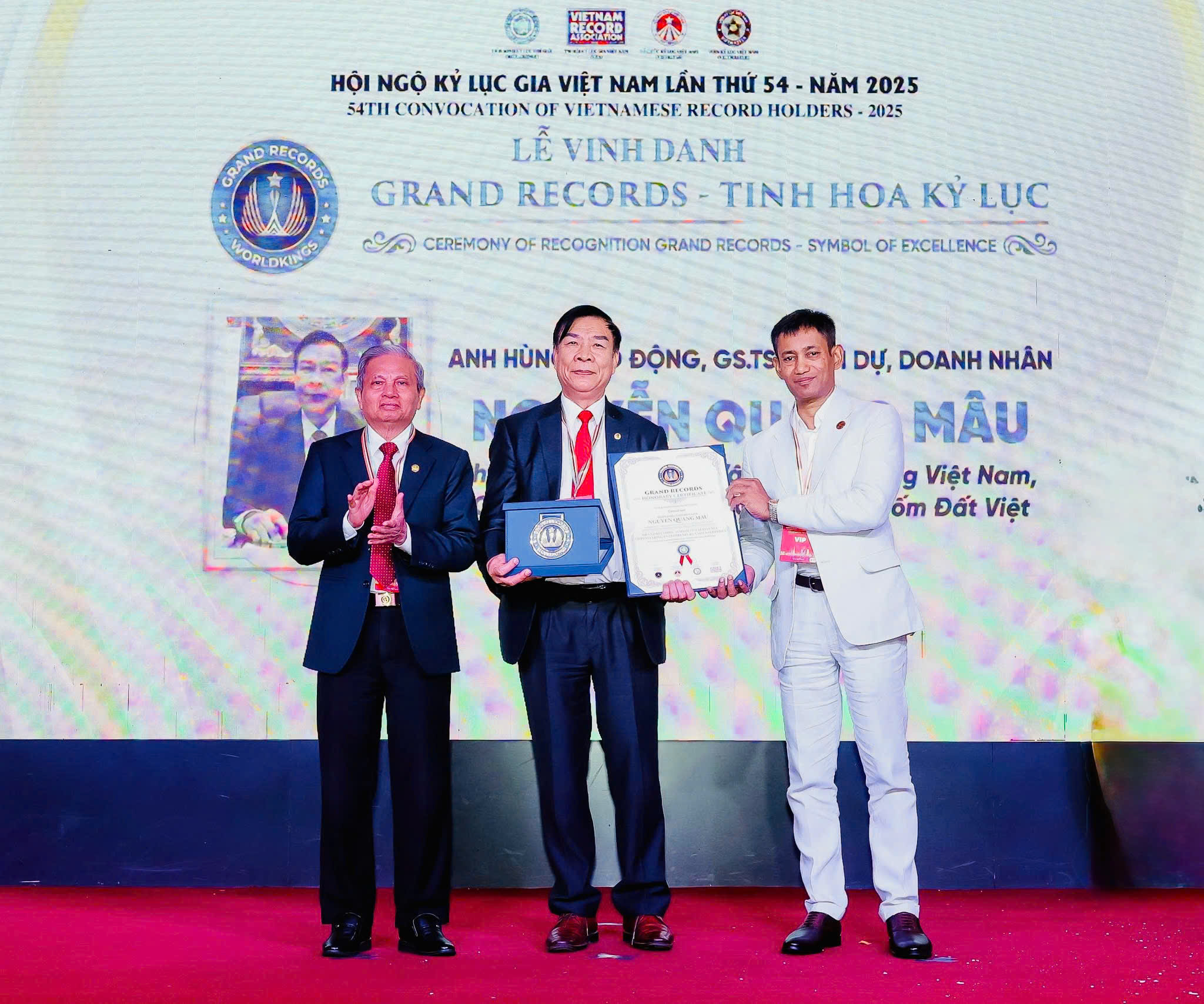 Tiến sĩ Biswaroop Roy Chowdhury - Chủ tịch Liên minh Kỷ lục Thế giới (WorldKings) và Tiến sĩ Lê Doãn Hợp - Nguyên Bộ trưởng Bộ Thông tin và Truyền thông, Chủ tịch Hội đồng Xác lập Kỷ lục Việt Nam trao bằng và huy hiệu GRAND RECORDS - TINH HOA KỶ LỤC đến Anh hùng Lao động, Giáo sư – Tiến sĩ danh dự, Kỷ lục gia Thế giới Nguyễn Quang Mâu.